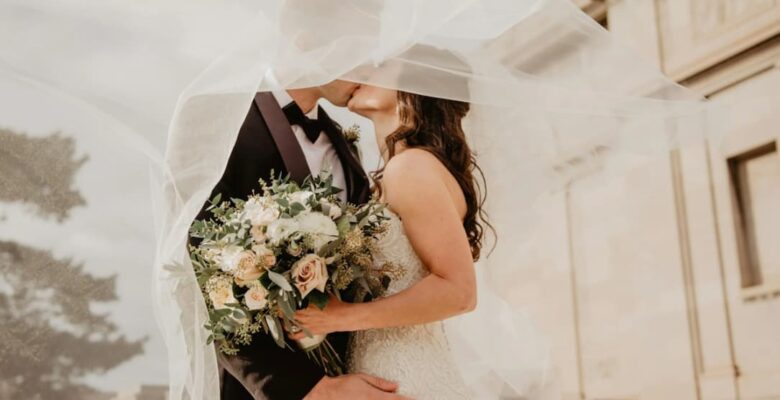 A bride and groom kissing under the bride's veil