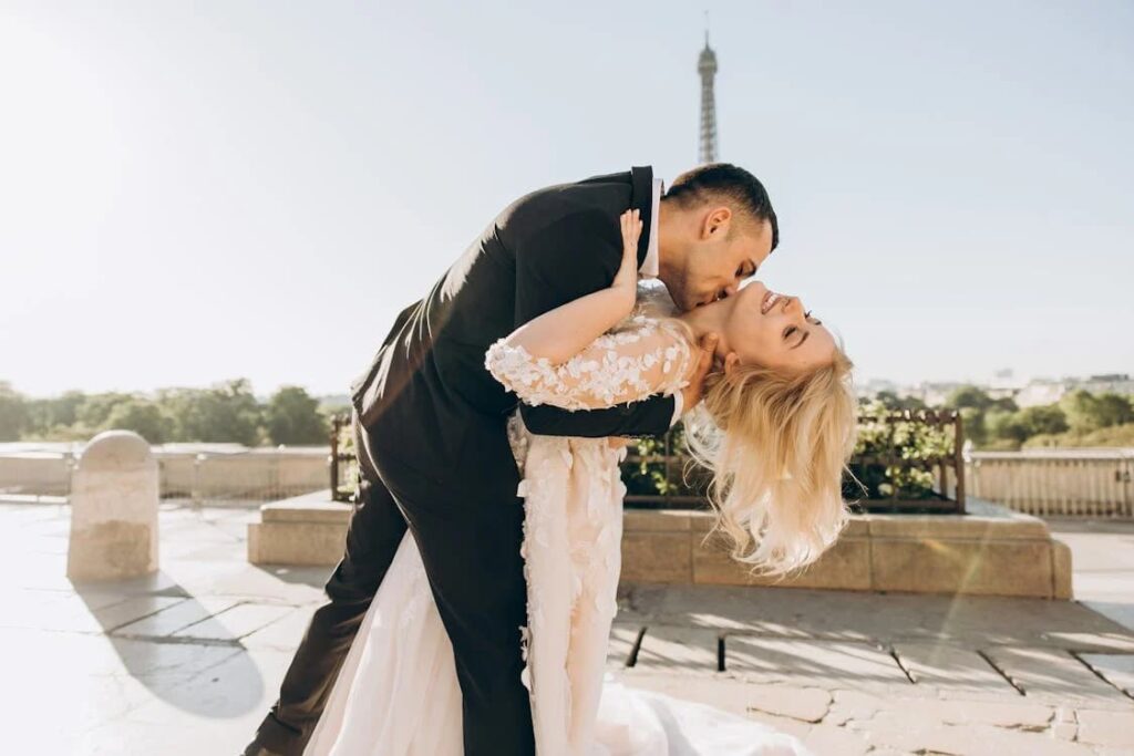 A bride and groom kissing in front of the Eiffel Tower