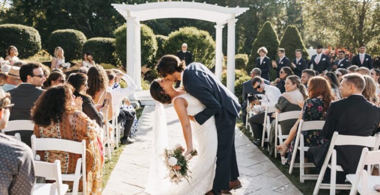 A couple kissing at the altar during a wedding ceremony with guests seated on either side