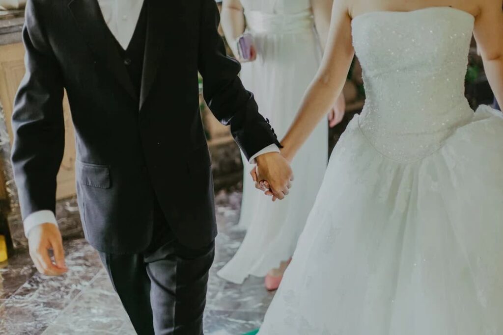 A newlywed couple holding hands, focus on the joined hands