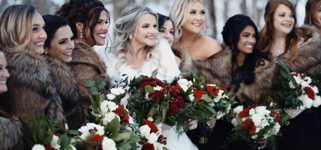 A group of women in fur stoles pose with bouquets in a winter setting