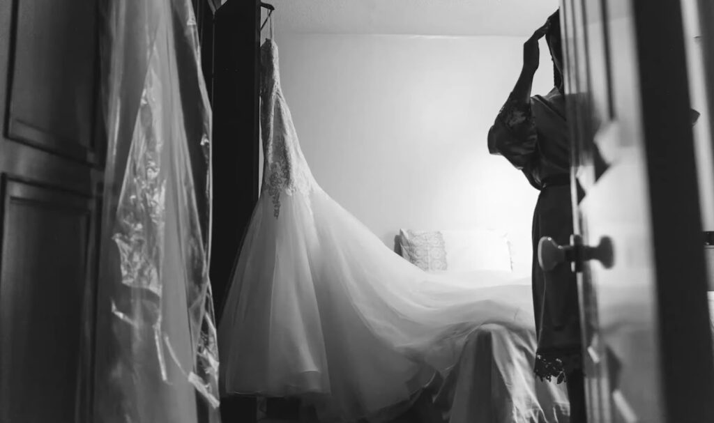 A wedding dress and a person adjusting its long train in a room