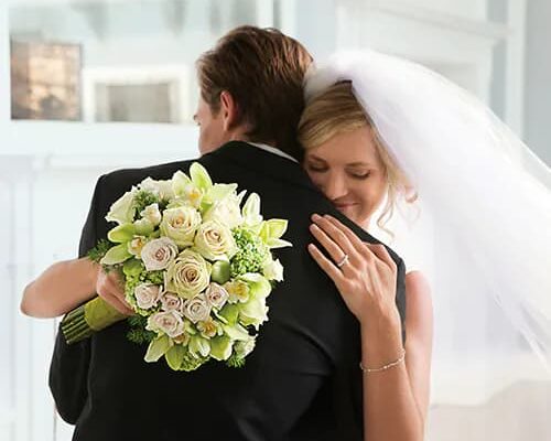 bride embraces groom with bouquet in hand