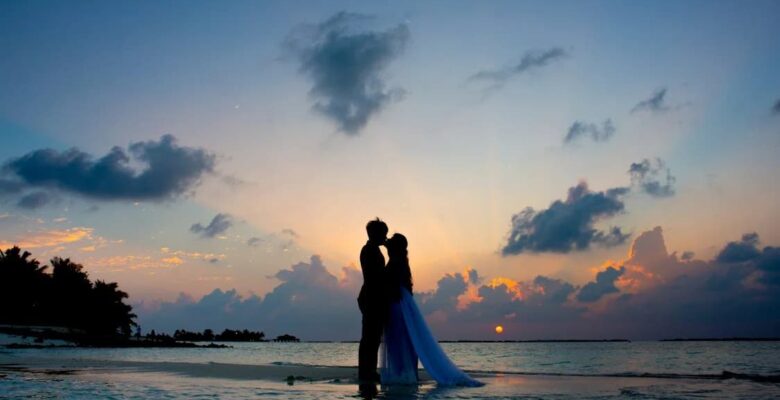 A silhouette of a couple kissing on a beach at sunset