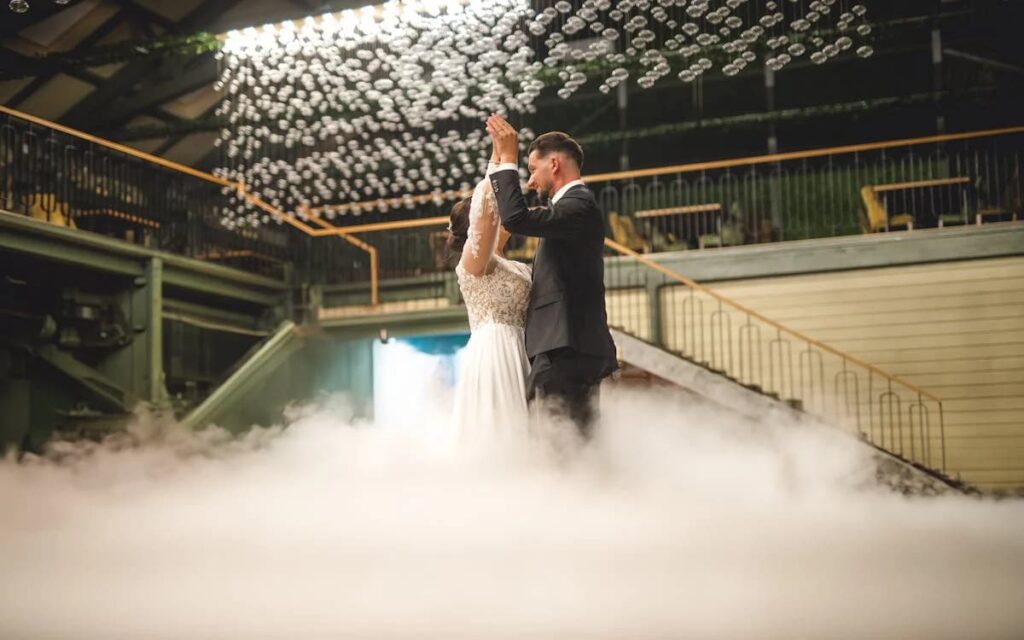 A couple dancing on a smoke-filled floor under a ceiling of lights