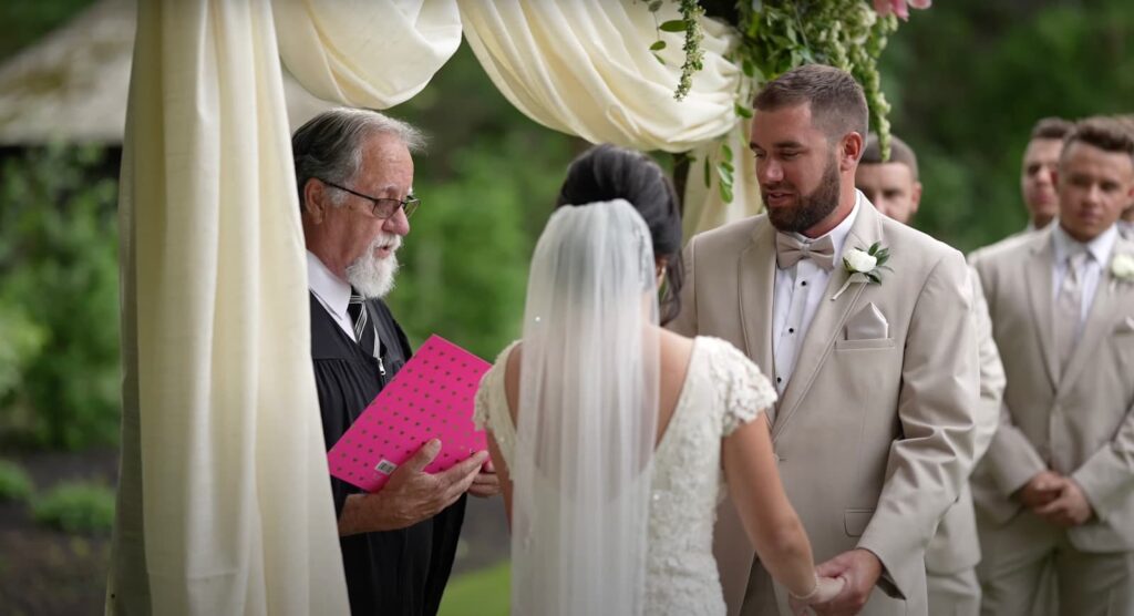 The groom holds the bride's hands during the ceremony