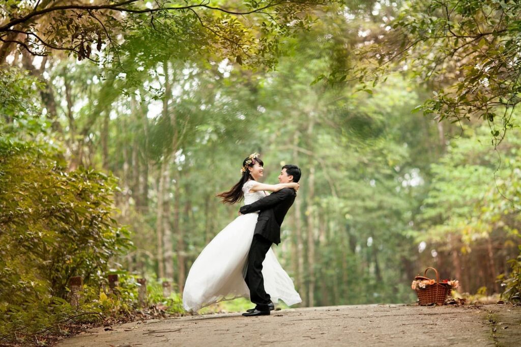 The groom holds the bride against the background of trees