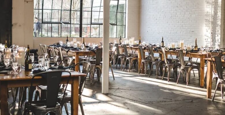 A sunny dining room with tables set for dining and a white brick wall