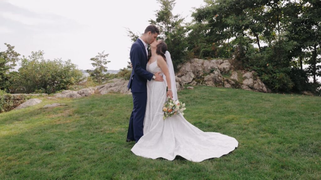 The newlyweds share a kiss in a grassy knoll
