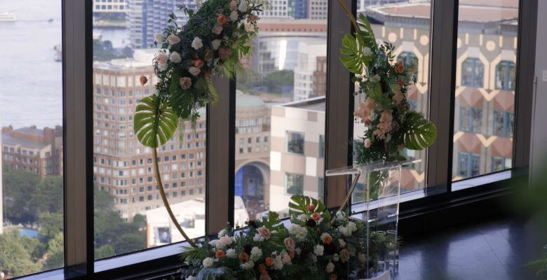 Elegant floral arrangements on clear pedestals by a window overlooking the city