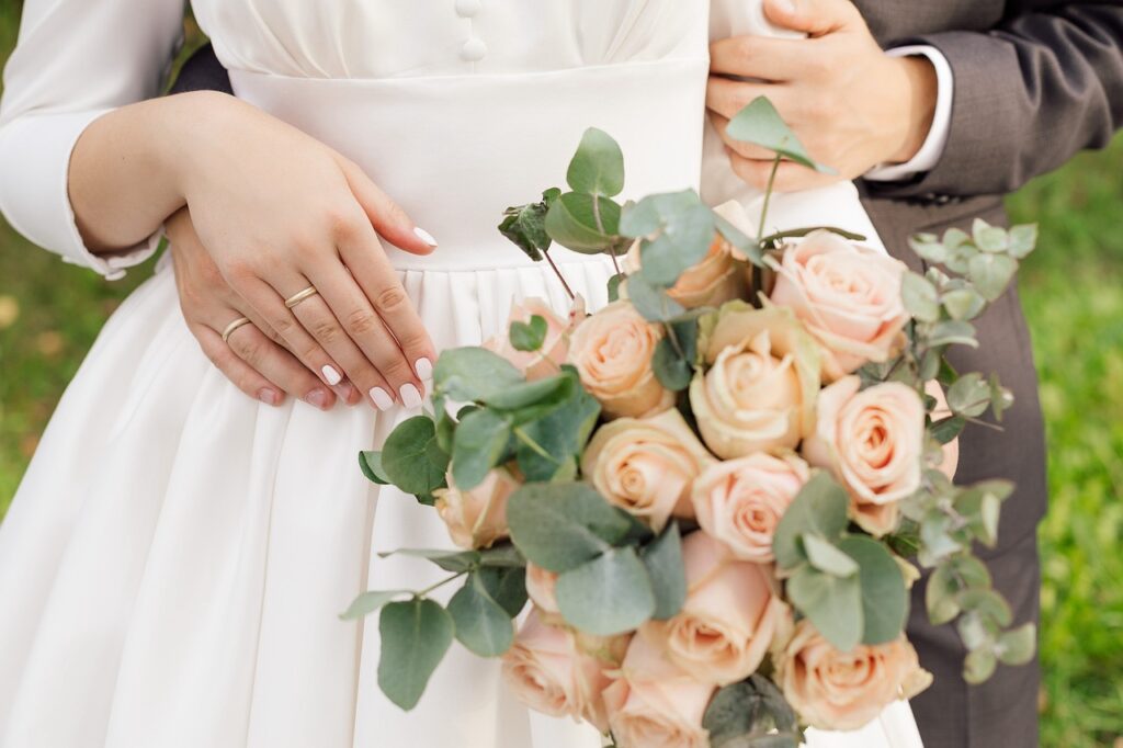 Hands of the bride and groom with rings and a bouquet